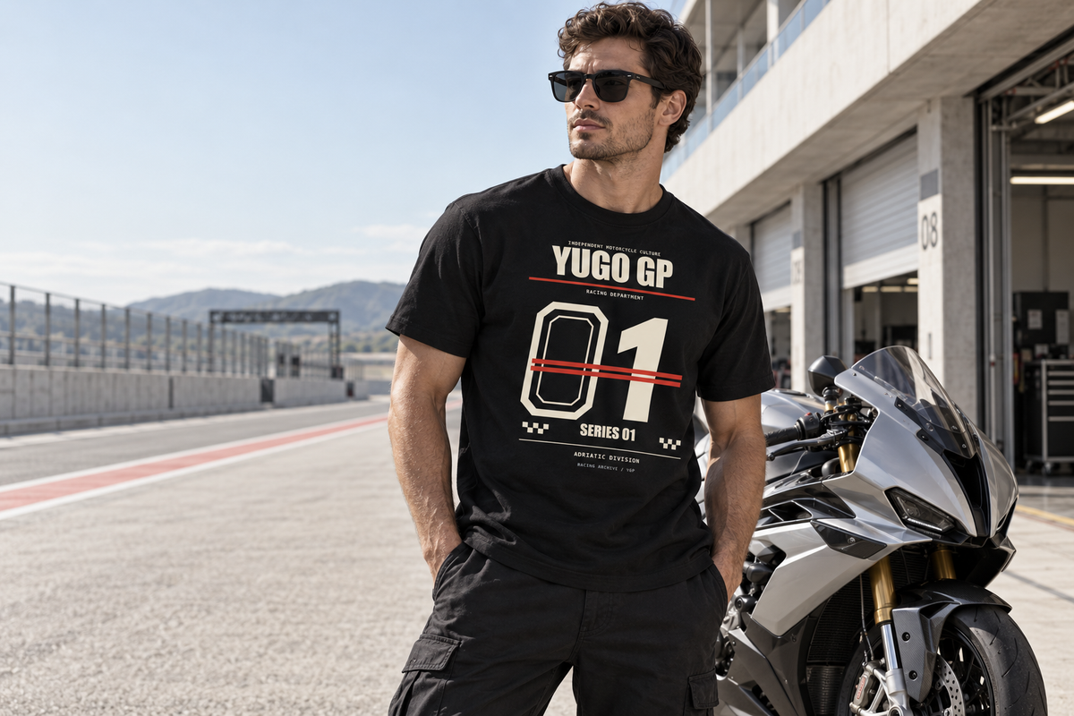 Rider wearing the Racing Department 01 tee beside a silver sport motorcycle in a sunlit paddock